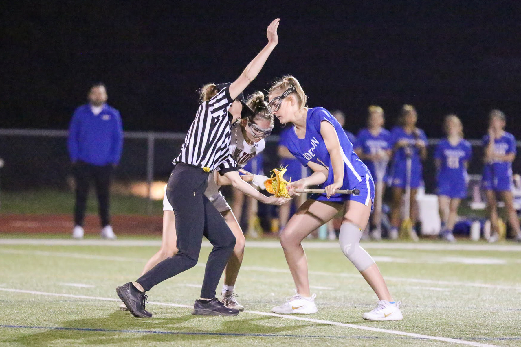 photo of a lacrosse official setting up a draw between two players